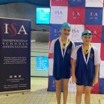 Two children wearing swimming hats and medals