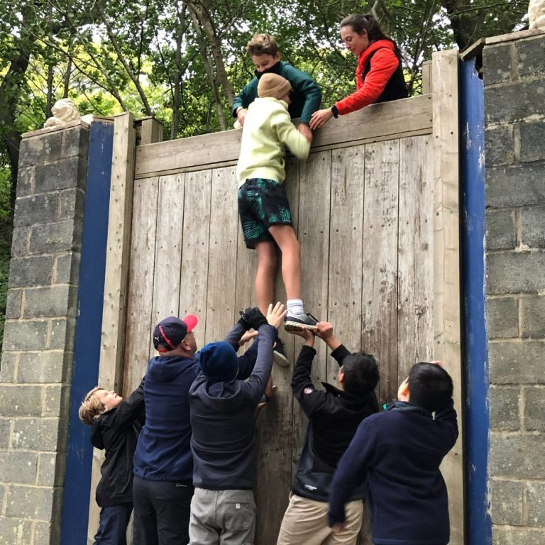 boy getting help to climb over a gate