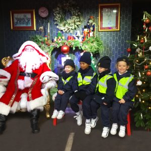 children in hi vis clothing sat next to Santa