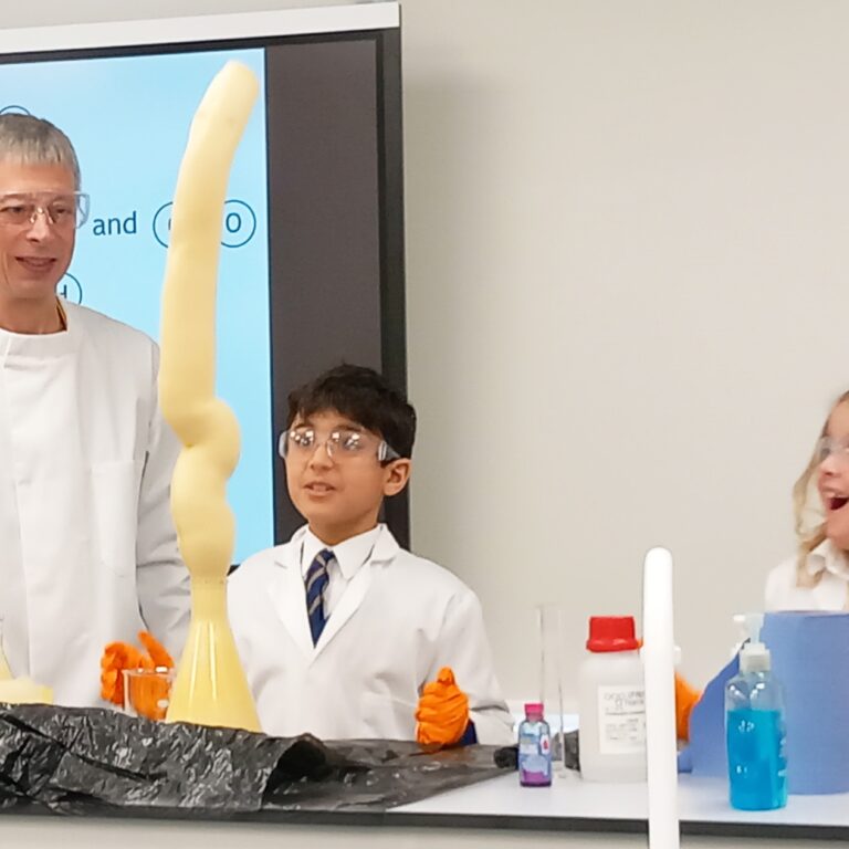 a teacher looking at 2 students finish a science experiment