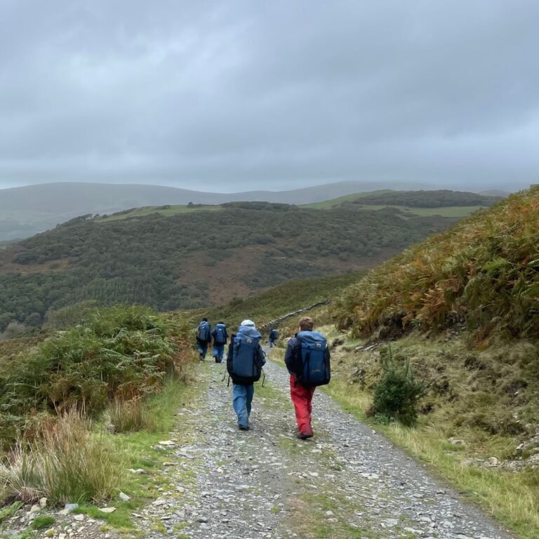 students in walking gear going down a mountain