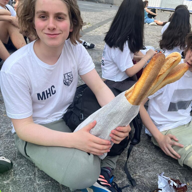 student holding a bag of baguettes